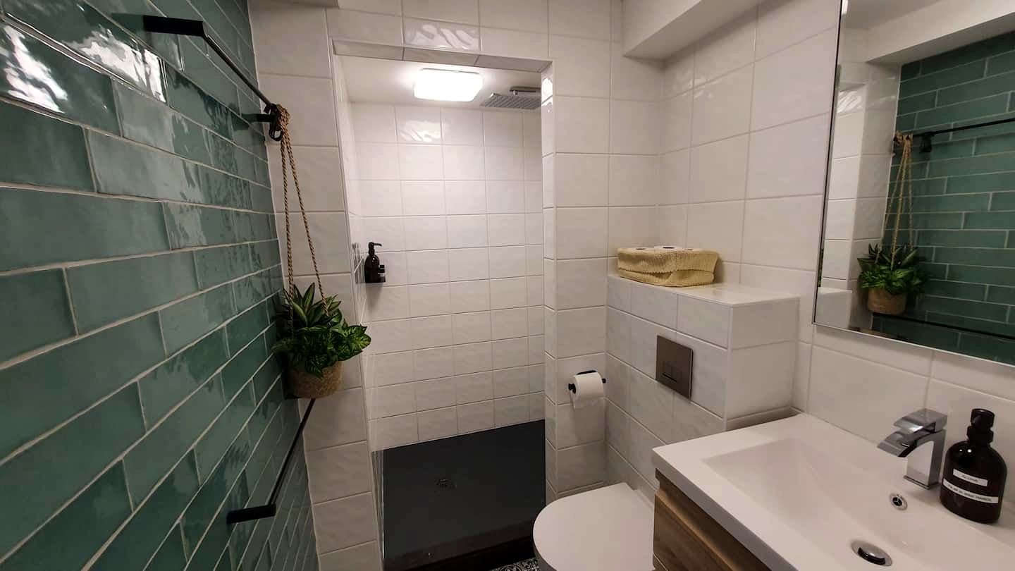 Badkamer met groene tegelwand en houten meubel