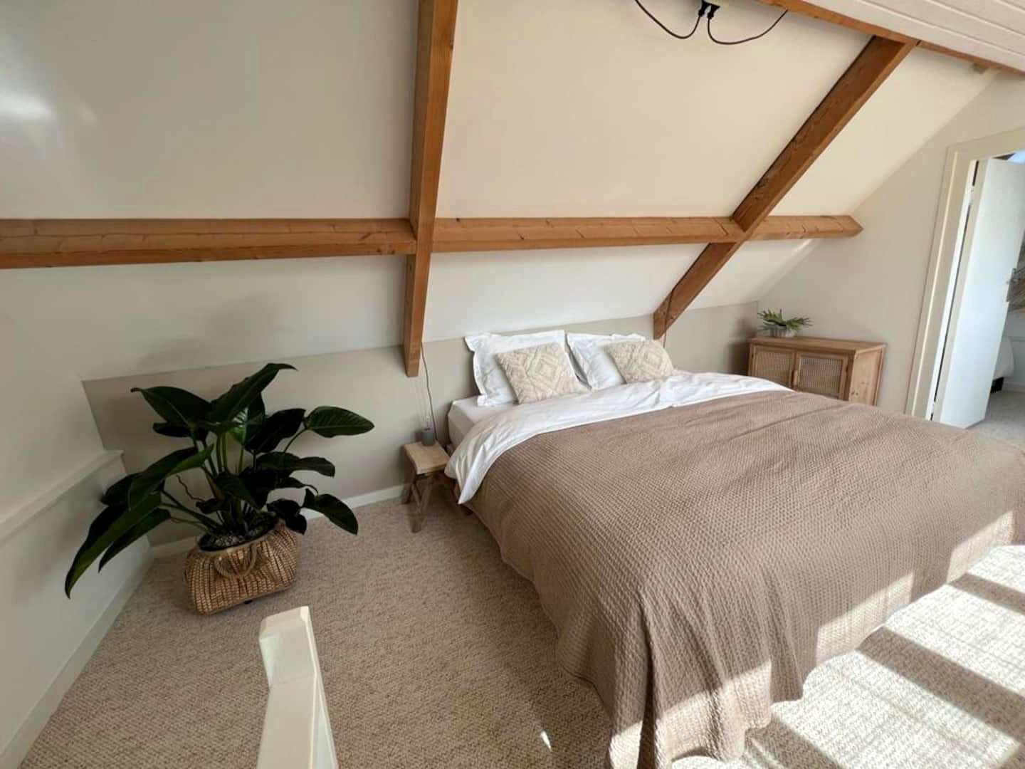 De slaapkamer met kingsize bed onder houten spanten
